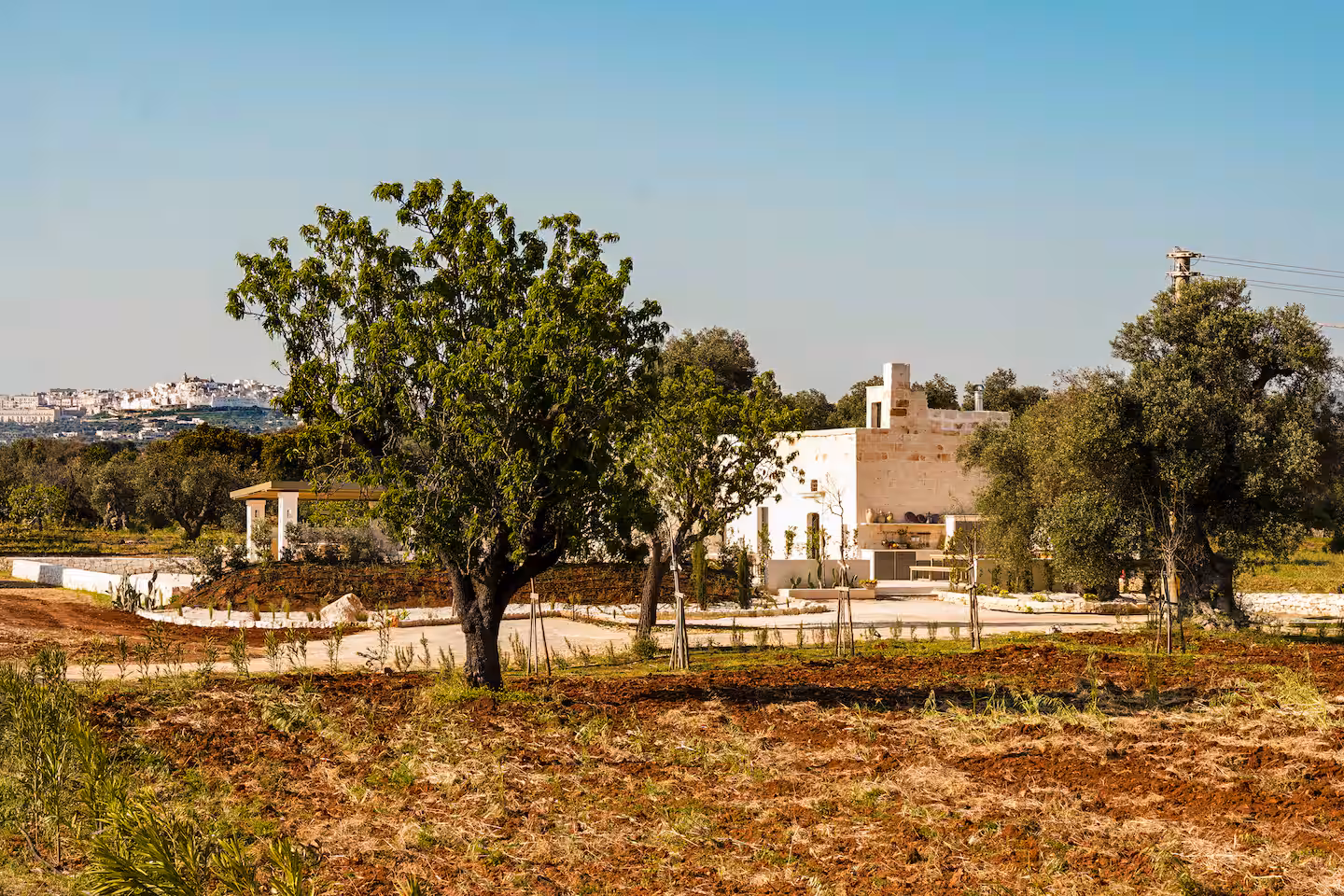 Restored stone masseria in the Puglian countryside, with the white town of Ostuni on the horizon